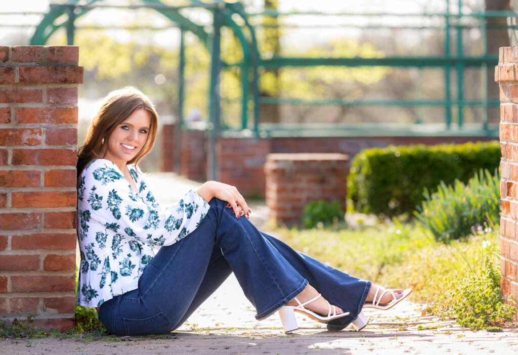 senior portrait sitting against a brick wall