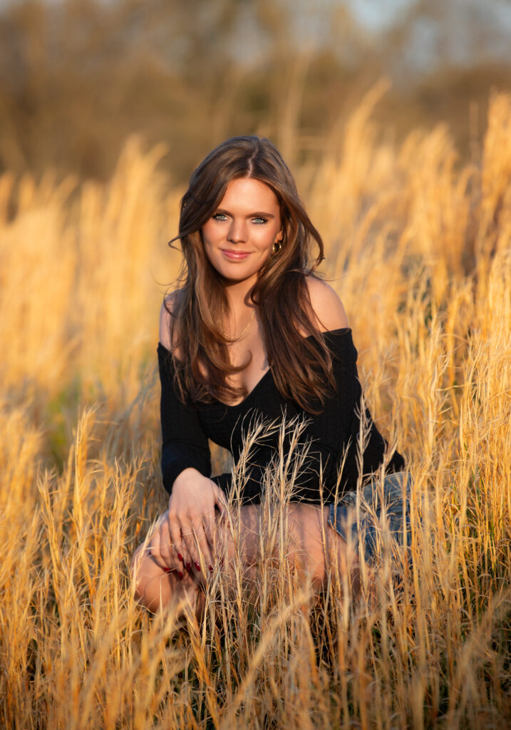 senior portrait in a field during golden hour