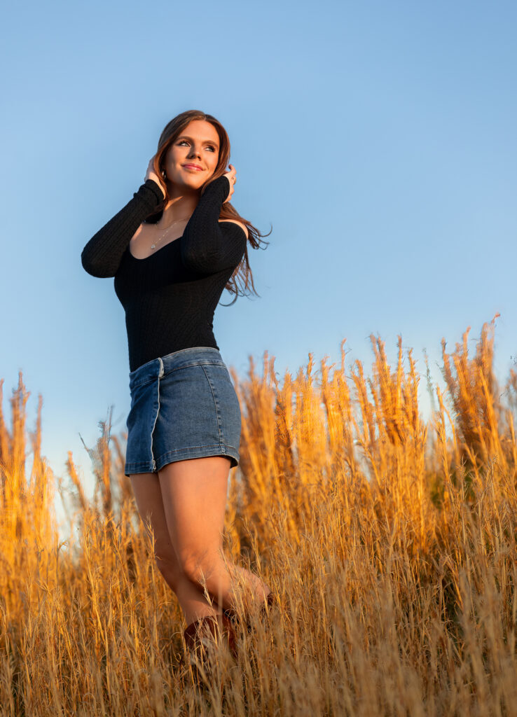 senior portrait in a field standing during golden hour