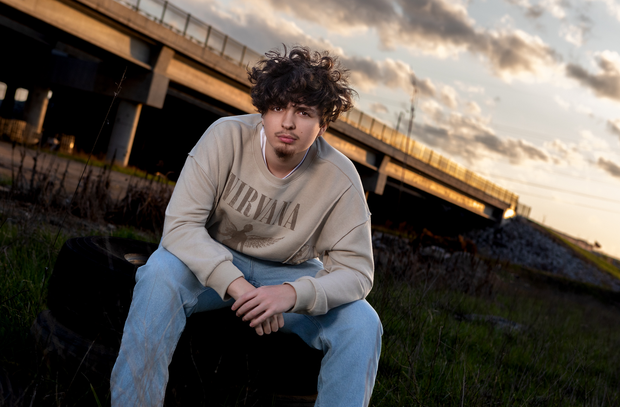 High school senior with bridge and dramatic sky in the background