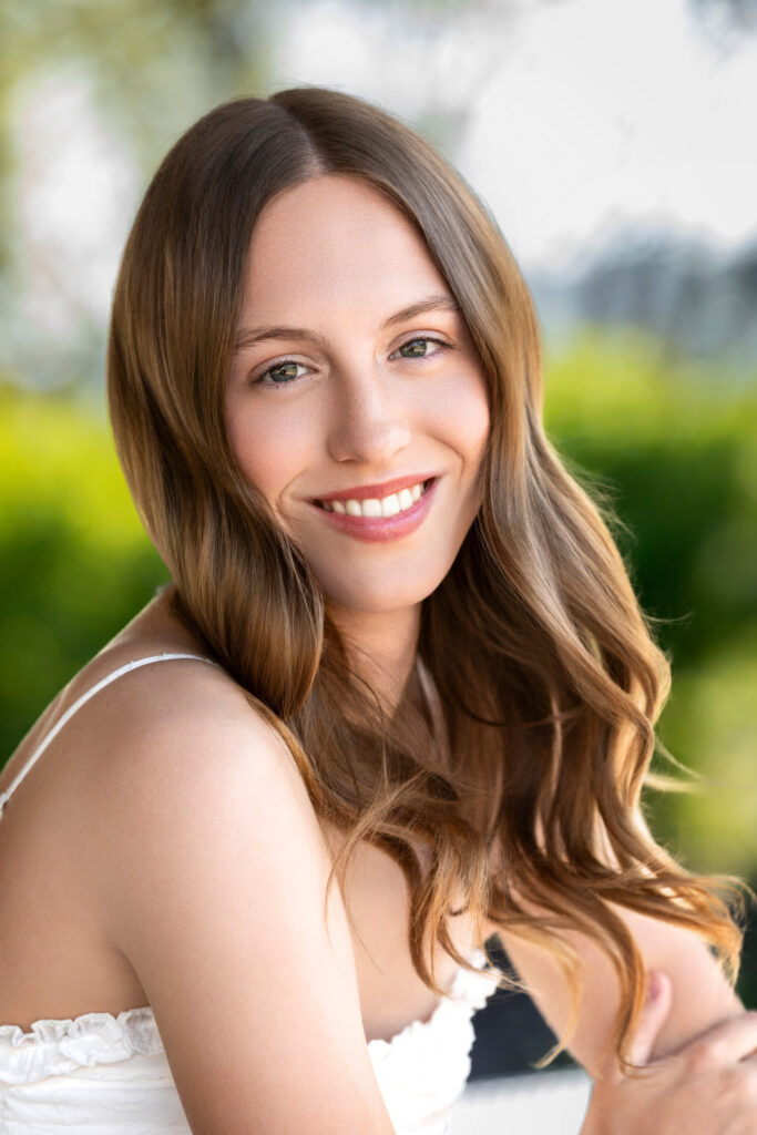 High school senior Spring season brown hair fair complexion in field at sunset arms crossed white shirt close up
