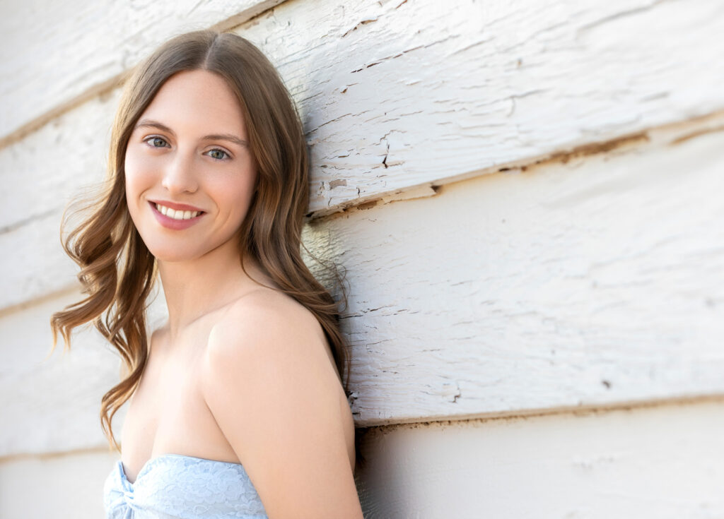 High school senior Spring season brown hair fair complexion leaning against white barn