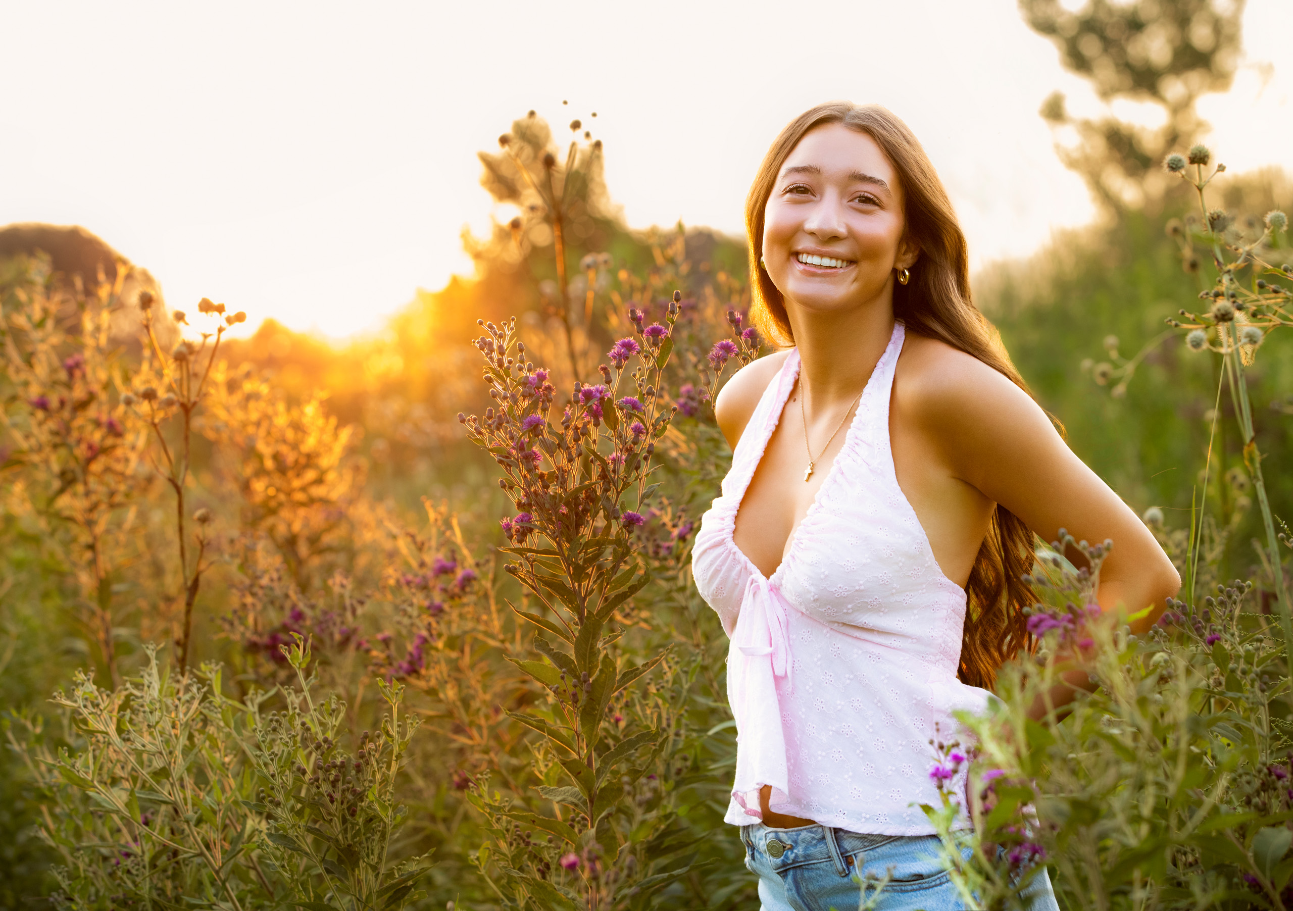 high school senior portrait in field at sunset