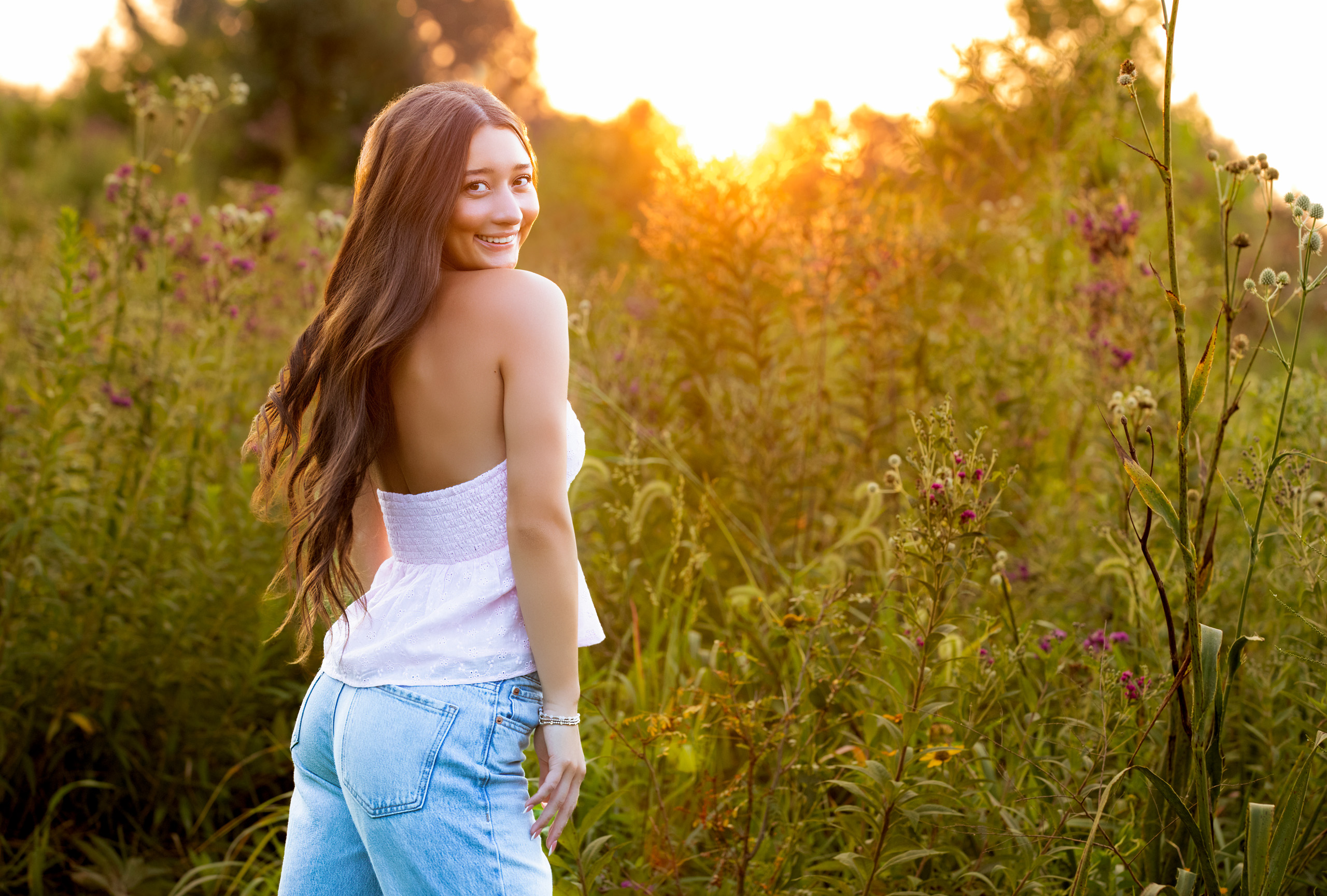 high school senior portrait in field at sunset