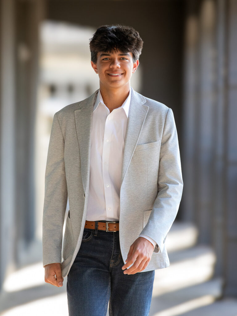 High School Senior Spring Session. Walking down sidewalk in a gray blazer.