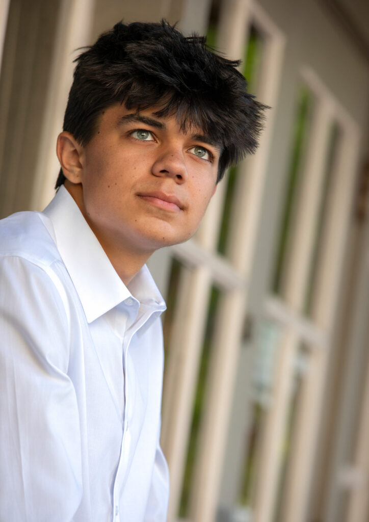 High school senior outside sitting on window sill in white oxford looking in the distace light green eyes