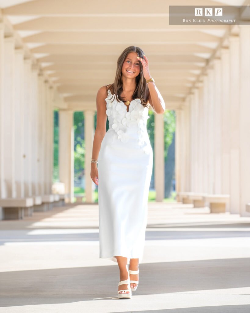 High school senior at the Muny chandelier in a long white dress walking hand by face
