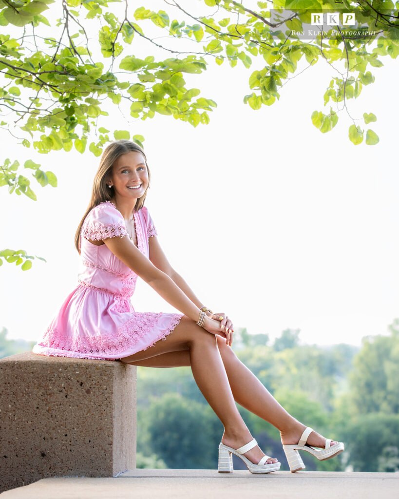 High school senior on concrete step in pink dress