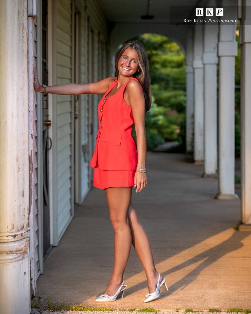 High school senior on porch in red suit dress full length