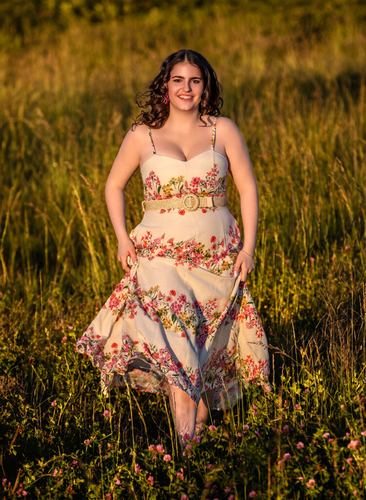 High School Senior Spring Session. Walking through field of pink flowers, floral dress curly hair