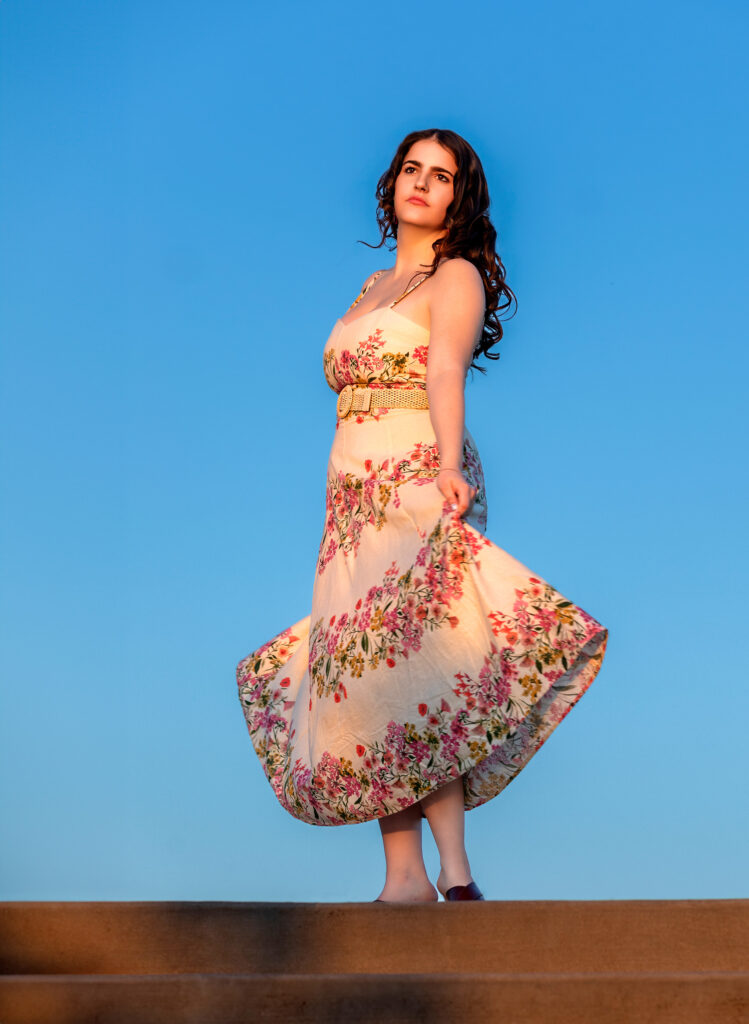High School Senior Spring Session. Standing at top of steps blue sky floral dress curly hair