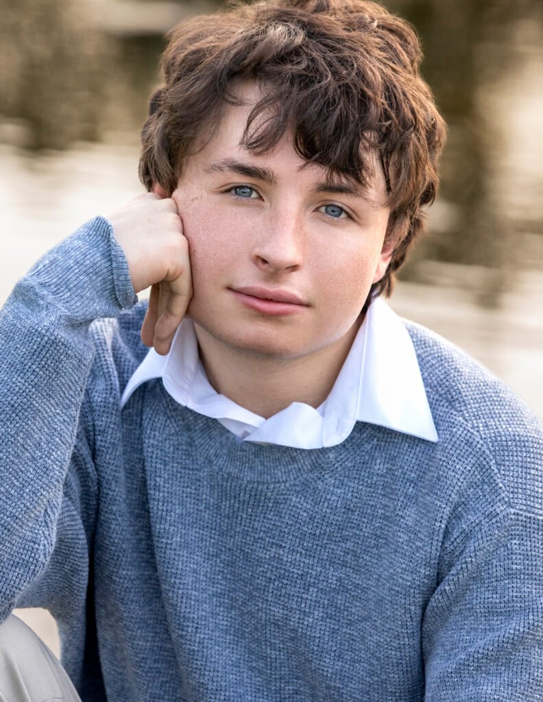 High school senior blue sweater collar shirt closeup hand on face