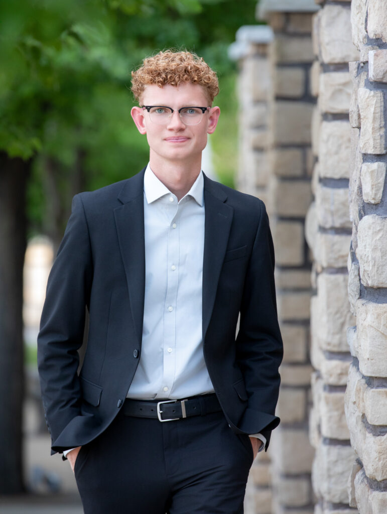 High school senior summer session walking by stone wall hands in pockets