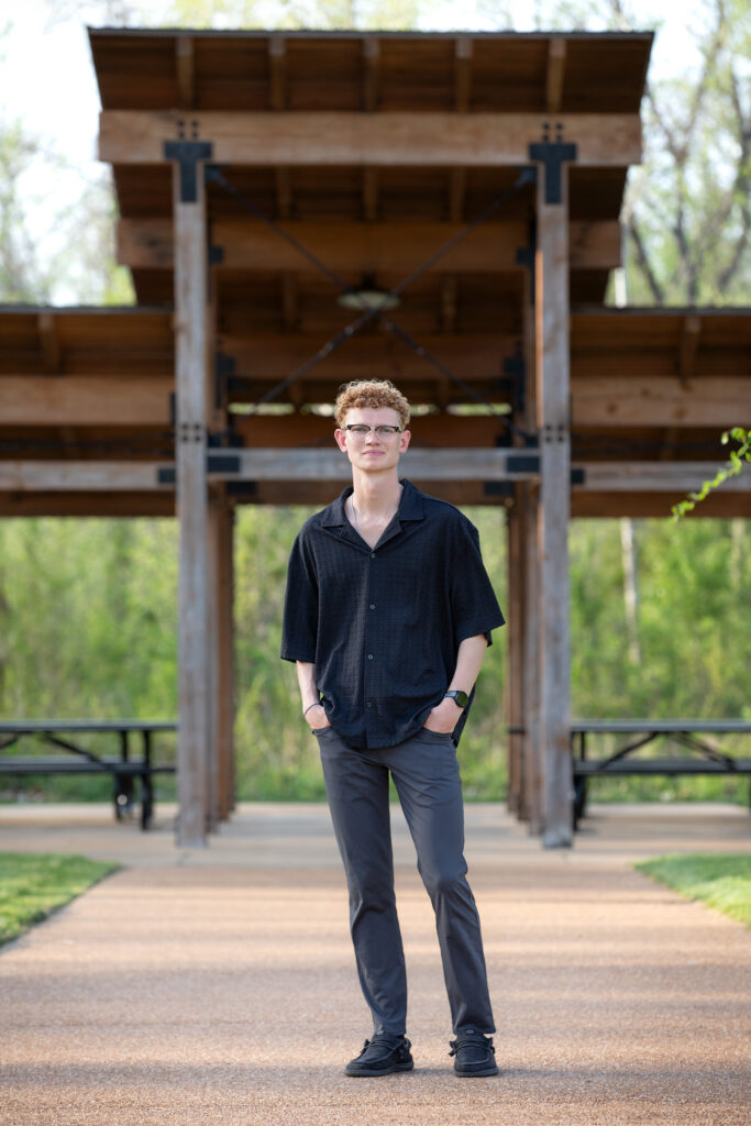High school senior standing on a walkway near a pavilion in Wildwood Park