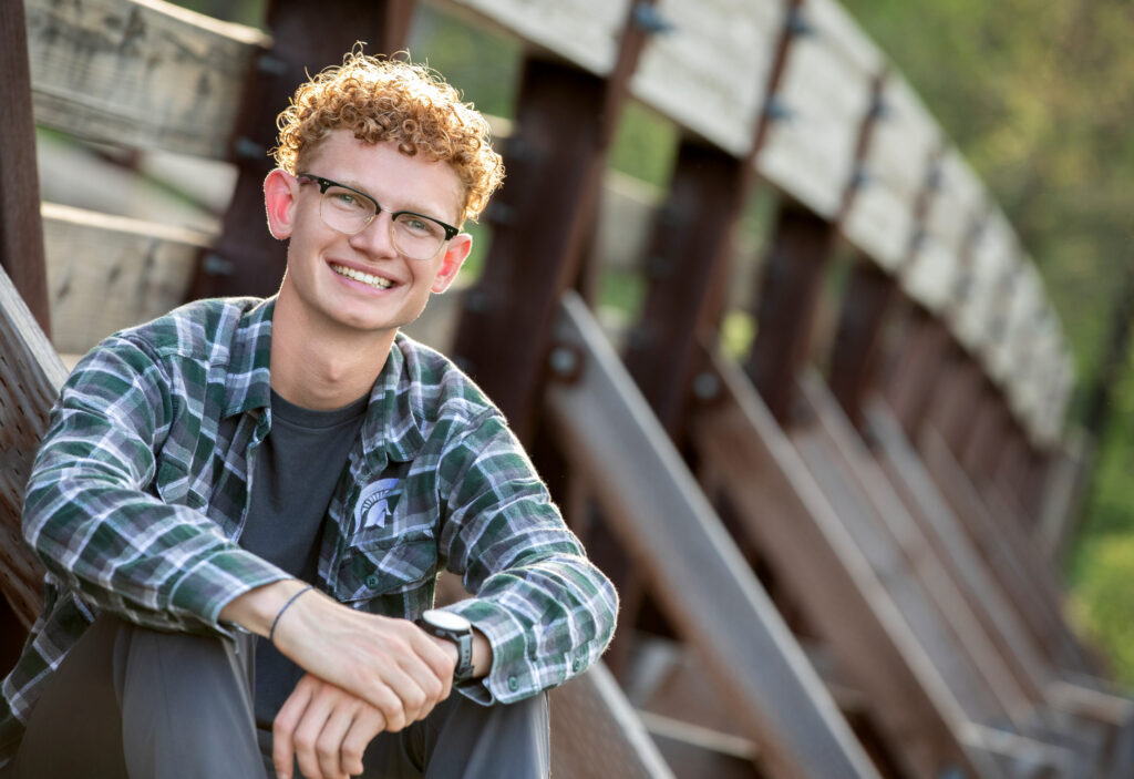 High school senior summer session sitting on the side of the bridge in Wildwood Park