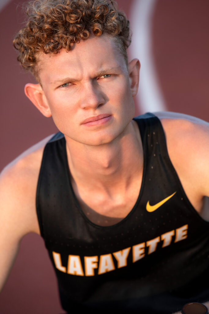 High school senior kneeling on the track at Lafayette High School